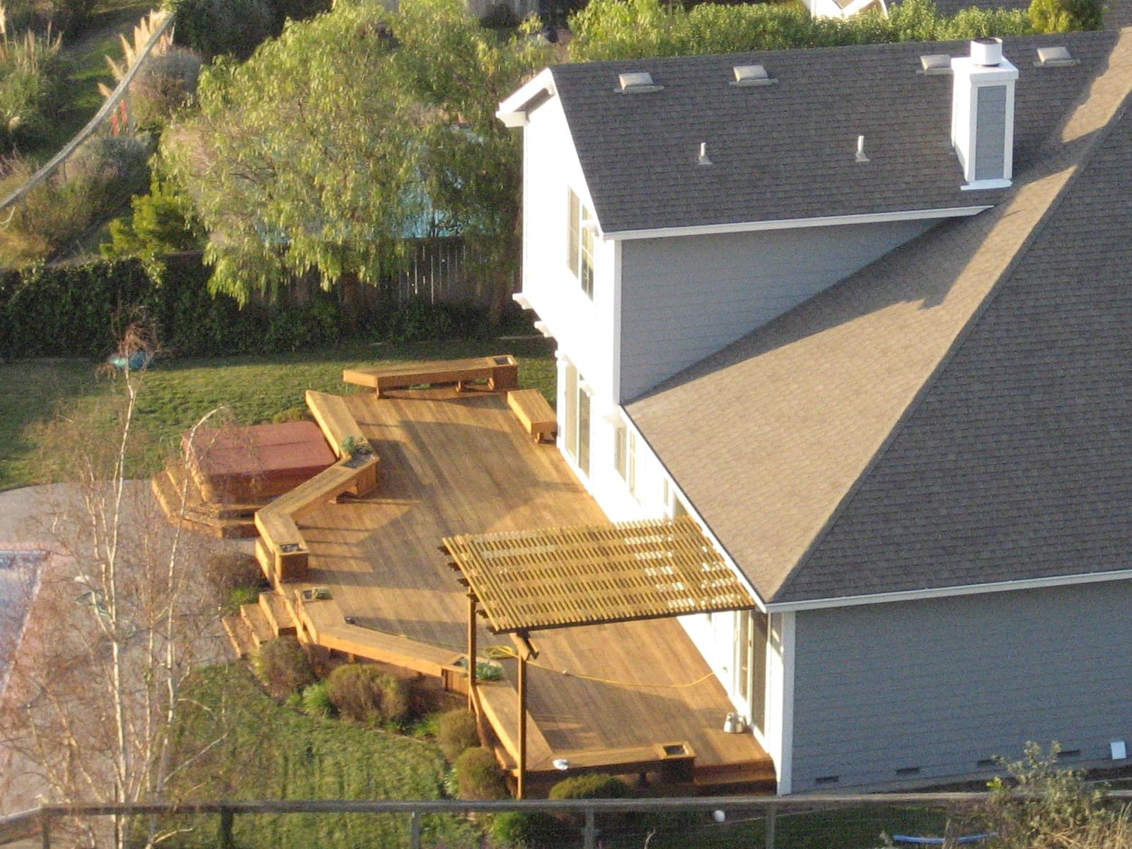 Timber backyard deck with steps and planting, a split-level idea on ordinary sloping ground.