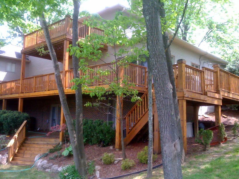 Cedar decking mid-stain, the line between weathered timber and a fresh coat that will not fix a failed board.